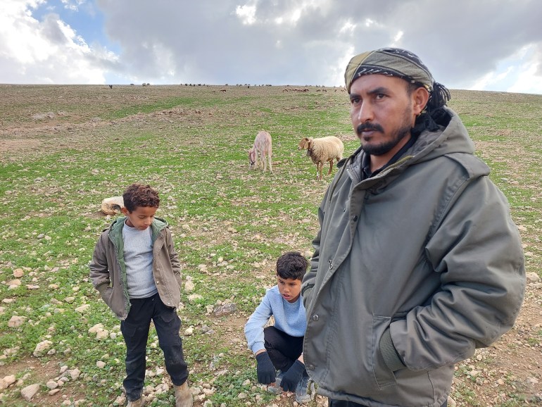 Suleiman standing in a field with two boys