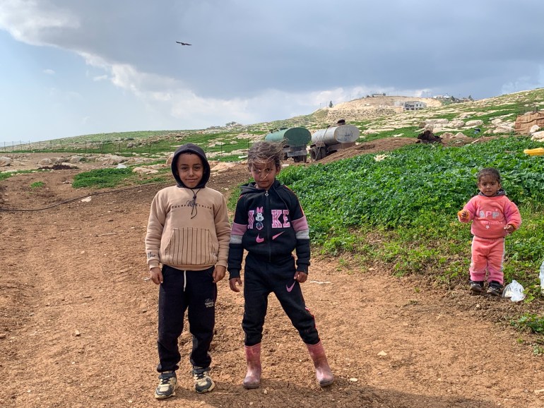 Crianças Mughayer al-deir com posto avançado de colonos ao fundo