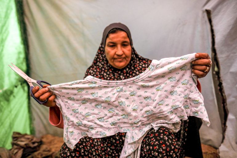 Woman holding up a cotton garment that she will cut into nappies