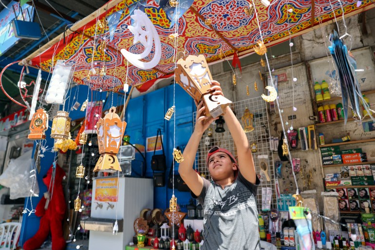 A Palestinian boy hangs a lantern as he sells products at a market, ahead of the holy fasting month of Ramadan, in Gaza City April 5, 2021. Picture taken April 5, 2021. REUTERS/Mohammed Salem