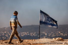 A teenage settler walks by an Israeli flag in Givat Eviatar near the Palestinian village of Beita in the Israeli-occupied West Bank [File: Amir Cohen/Reuters]
