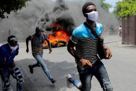 Men run next to burning tyres during a protest against gang violence, in Port-au-Prince, Haiti, August 14, 2023 [File: Ralph Tedy Erol/Reuters]