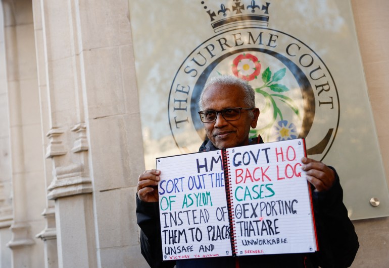 A protestor holds a placard outside of the Supreme Court, on the day the Supreme Court delivers its ruling on whether the government can go ahead with its plan to deport migrants to Rwanda, in London, Britain, November 15, 2023