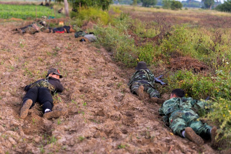 Les combattants anti-putsch rampent sur le sol alors qu'ils combattent l'armée à Sagaing.  Ils se battent dans les champs agricoles.