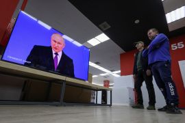 People watch a TV broadcast of Russian President Vladimir Putin's annual address to the Federal Assembly at a shop in Simferopol, Crimea February 29, 2024. REUTERS/Alexey Pavlishak