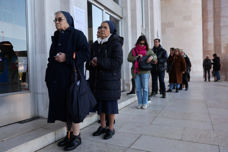 People queue to vote, outside a polling station during the general election in Lisbon, Portugal