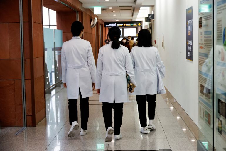 Three doctors walking down a corridor in South Korea. They are walking away from the camera.