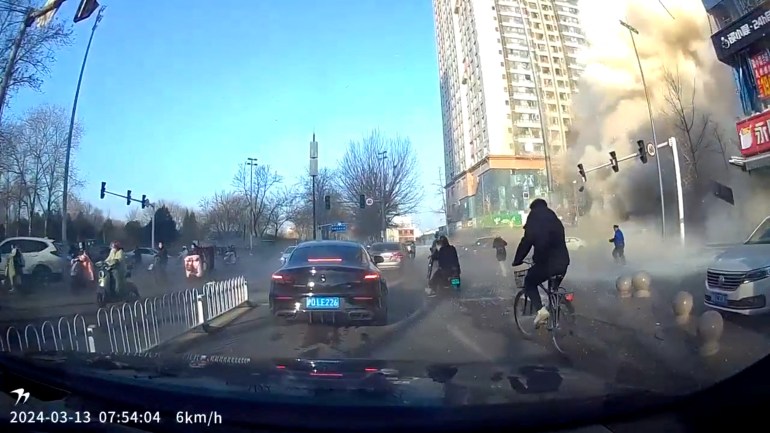 Clip from Dashcam showing people - inlcuding a man on a bike - rushing to escape after the explosion. There is a man on a bike, and lots of dust in the air.