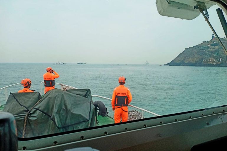 Members of Taiwan's coast guard during the rescue mission. They are wearing high-vis suits and standing on the deck. The sea looks calm.