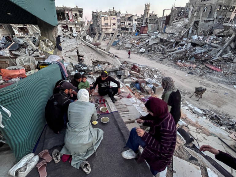 Palestinian members of Al-Khlout family break their fast on the rubble of their house which was destroyed during Israel's military offensive, during the holy month of Ramadan, as the conflict between Israel and Hamas continues, in Beit Lahia in the northern Gaza Strip, March 13, 2024. REUTERS/Mahmoud Issa