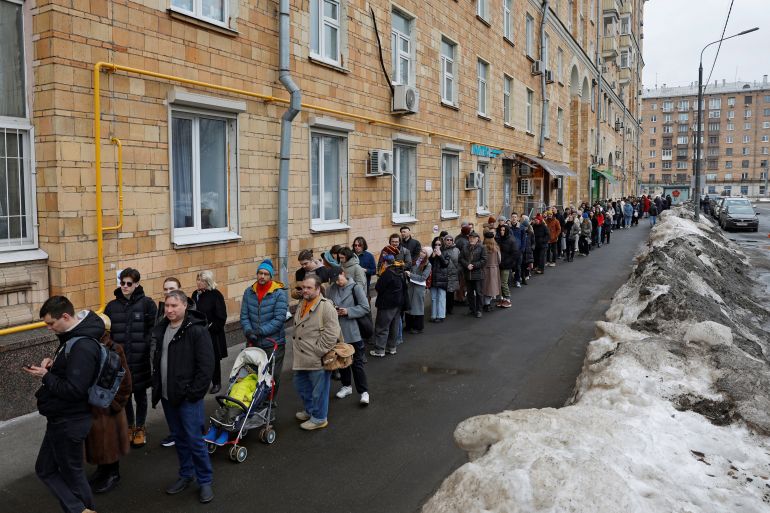 People stand in a line to enter a polling station around noon on the final day of the presidential election in Moscow, Russia, March 17