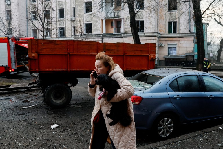 A person talks on the phone holding a dog at a site of a building, damaged during a Russian missile strike, amid Russia's attack on Ukraine, in Kyiv, Ukraine March 21, 2024. REUTERS/Alina Smutko