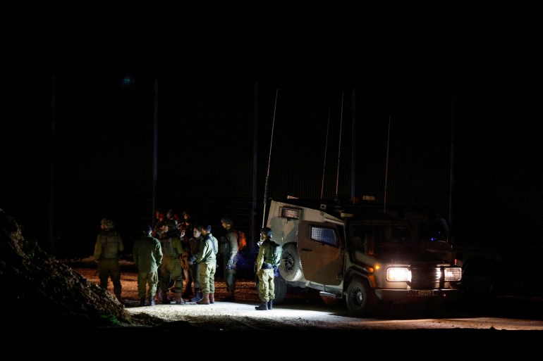 Israeli soldiers stand on the border with Gaza, as aid trucks carrying humanitarian supplies wait to enter Gaza