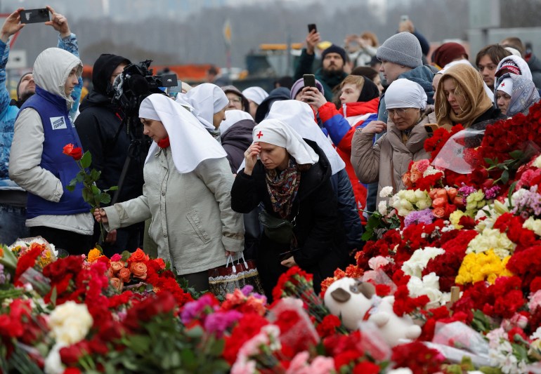 Am 24. März 2024 legen Menschen Blumen an einem provisorischen Denkmal für die Opfer eines Schießangriffs nieder, der vor dem Konzertort Crocus City Hall in der Region Moskau, Russland, errichtet wurde. REUTERS/Maxim Schemetow