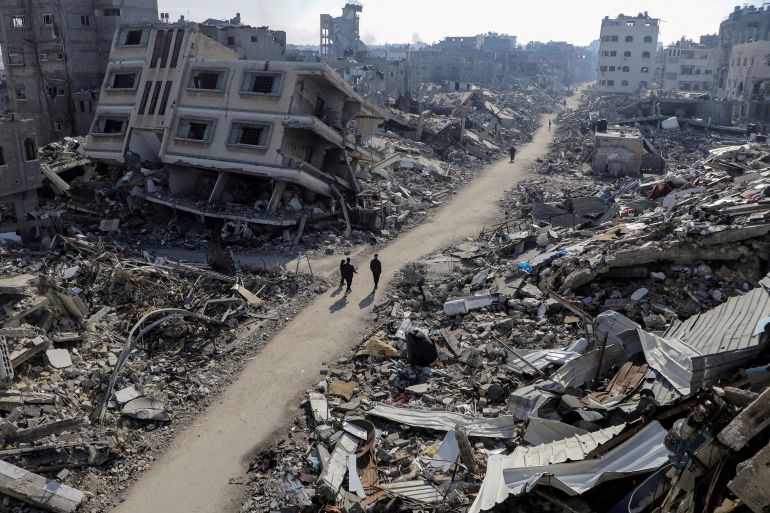 FILE PHOTO: Palestinians walk past destroyed houses, amid the ongoing conflict between Israel and Hamas, in Jabalia refugee camp, in the northern Gaza Strip February 22, 2024. REUTERS/Mahmoud Issa/File Photo