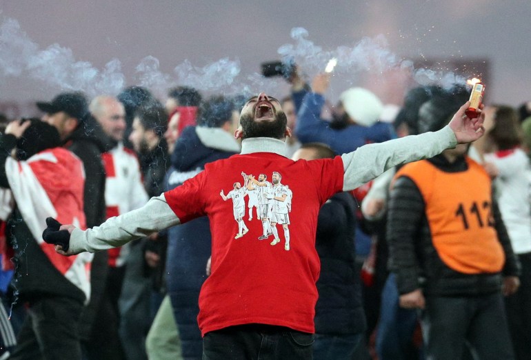 Soccer Football - Euro 2024 Qualifier - Play-off - Georgia v Greece - Boris Paichadze Dinamo Arena, Tbilisi, Georgia - March 26, 2024 A Georgia fan with a flare on the pitch celebrates after qualifying for Euro 2024 REUTERS/Irakli Gedenidze TPX IMAGES OF THE DAY