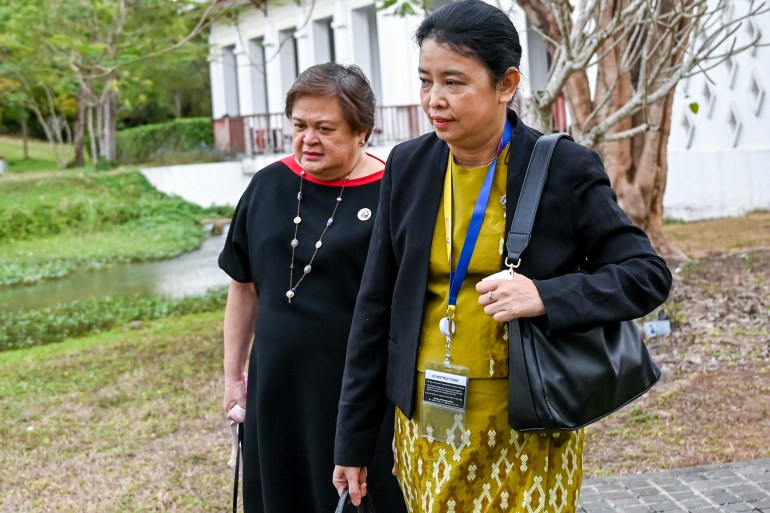 Myanmar Foreign Ministry official Marlar Than Htike in Luang Prabang. She is walking with a Philippines official, She is wearing a traditional outfit with a jacket and has her bag over her shoulder.