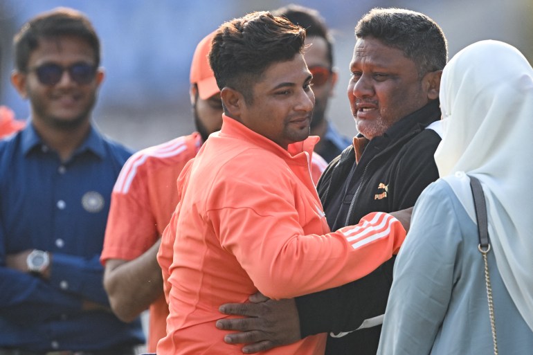India's Sarfaraz Khan (C,L) greets his father before his debut match at the Niranjan Shah stadium formerly known as Saurashtra Cricket Association in Rajkot on February 15, 2024, before the start of third Test cricket match between India and England. (Photo by Punit PARANJPE / AFP) / -- IMAGE RESTRICTED TO EDITORIAL USE - STRICTLY NO COMMERCIAL USE -- - -- IMAGE RESTRICTED TO EDITORIAL USE - STRICTLY NO COMMERCIAL USE --