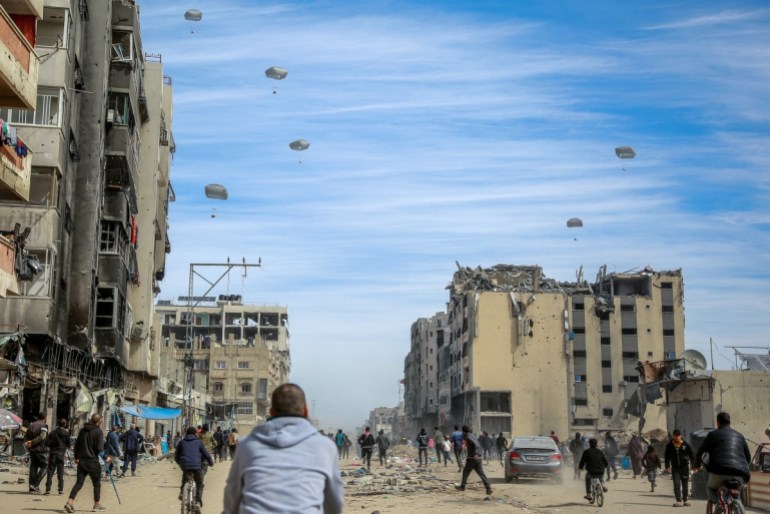 Palestinians run along a street as humanitarian aid is airdropped in Gaza City on March 1, 2024. 