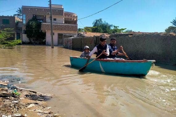 Residents row a boat to cross a flooded street after heavy rains in Gwadar in Balochistan province on March 2, 2024. (Photo by AFP)
