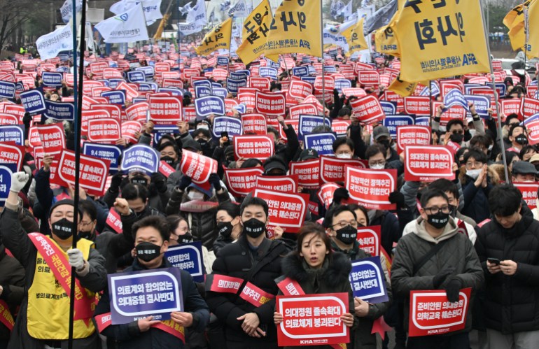 A crowd of doctors on the streets of Seoul. They are carrying placards showing their opposition to plans to increase the number of places at medical schools