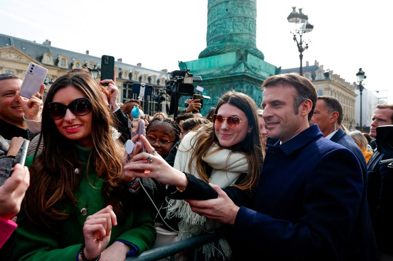 French President Emmanuel Macron, right, poses for a selfie with the public after a ceremony to seal the right to abortion in the French constitution, on International Women's Day