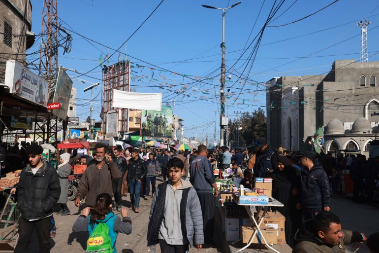 Palestinians walk past stalls set up in a street in Rafah, in the southern Gaza Strip on March 10
