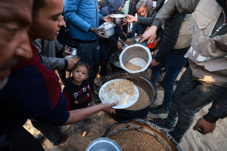 Displaced Palestinians collect food donated by a charity before an iftar meal, the breaking of fast, on the first day of the Muslim holy fasting month of Ramadan, in Rafah
