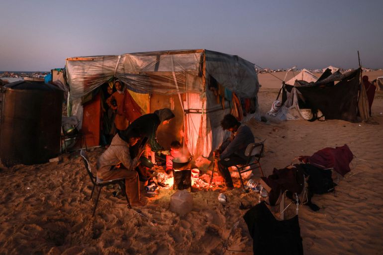 Displaced Palestinians prepare an iftar meal, the breaking of fast, on the first day of the Muslim holy fasting month of Ramadan, outside a tent in Rafah