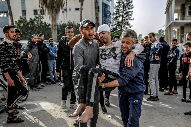 EDITORS NOTE: Graphic content / Two men carry an injured man outside the Ahli Arab hospital in Gaza City on March 27, 2024 amid the ongoing conflict in the Gaza Strip between Israel and the Palestinian militant group Hamas. (Photo by AFP)