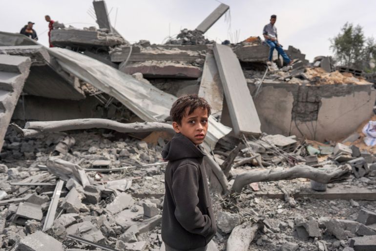A Palestinian youth inspects the debris of a building, following Israeli bombardment