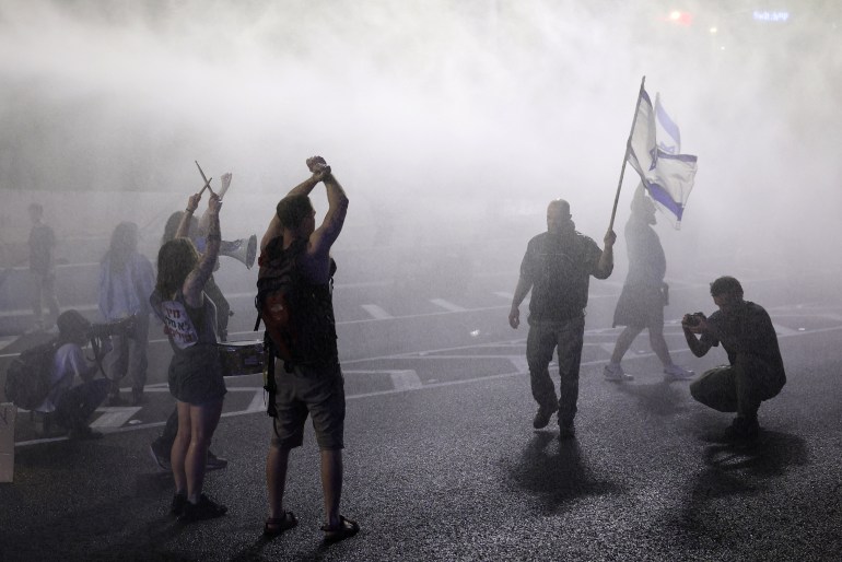 A polícia israelense borrifa água nos manifestantes enquanto eles bloqueiam uma estrada durante uma reunião de parentes de reféns israelenses mantidos em Gaza desde os ataques de 7 de outubro por militantes do Hamas, em frente ao Ministério da Defesa na cidade costeira israelense de Tel Aviv