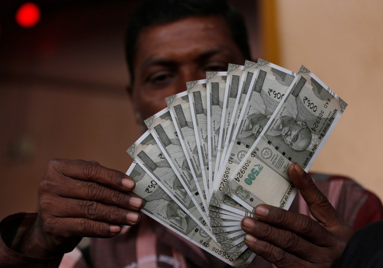 An Indian man makes formations with new currency notes of 500 Indian rupees that he received at an Agriculture Produce Market Committee (APMC) market in Ahmadabad, India, Wednesday, Nov. 23, 2016. Delivering one of India's biggest-ever economic upsets, Prime Minister Narendra Modi on November 8 declared the bulk of Indian currency notes no longer held any value and told anyone holding those bills to take them to banks. (AP Photo/Ajit Solanki)
