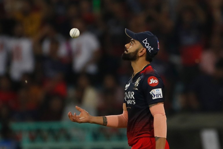 Royal Challengers Bangalore's Virat Kohli tosses the ball after taking the catch of Lucknow Super Giants' Ayush Badoni.