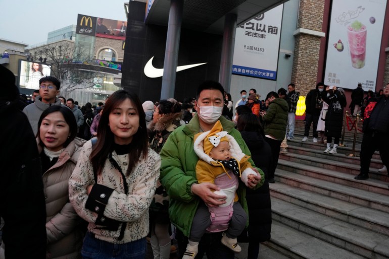 A man carries a child at a shopping mall in Beijing, Dec. 30, 2023. China’s population dropped by 2 million people in 2023 in the second straight annual drop as births fell and deaths jumped. (AP Photo/Ng Han Guan)