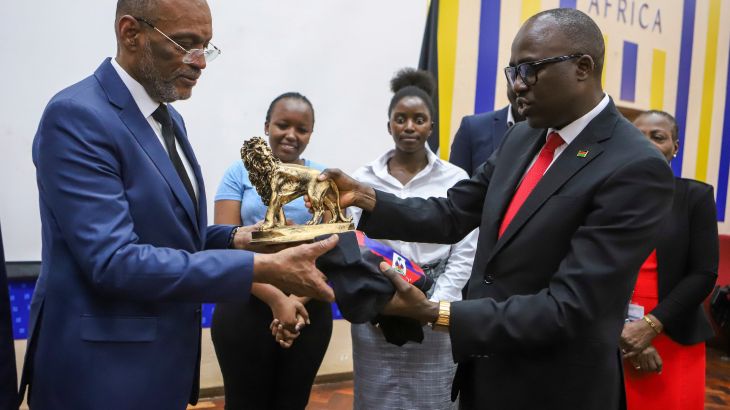Ariel Henry accepting a statue of a golden lion as a gift from Kenya's foreign minister