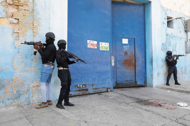 Three armed policemen stand guard outside a prison in Port-au-Prince
