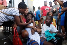The relative of a victim found dead in the street reacts after an overnight shooting in the Petion-Ville neighbourhood of Port-au-Prince. [Odelyn Joseph/AP Photo]