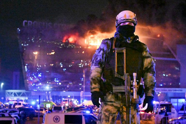 A Russian Rosguardia (National Guard) servicemen secures an area as a massive blaze seen over the Crocus City Hall on the western edge of Moscow, Russia, Friday, March 22, 2024. Several gunmen have burst into a big concert hall in Moscow and fired automatic weapons at the crowd, injuring an unspecified number of people and setting a massive blaze in an apparent terror attack days after President Vladimir Putin cemented his grip on the country in a highly orchestrated electoral landslide. (AP Photo/Dmitry Serebryakov)