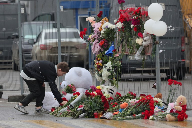 A boy places flowers at the fence next to the Crocus City Hall, on the western edge of Moscow, Russia, Saturday, March 23, 2024, following an attack Friday, for which the Islamic State group claimed responsibility. Russian officials say more than 90 people have been killed by assailants who burst into a concert hall and sprayed the crowd with gunfire. (AP Photo/Vitaly Smolnikov)