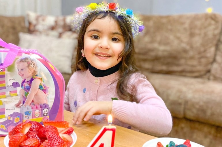 Salma with flowers in her hair in front of her fourth birthday cake