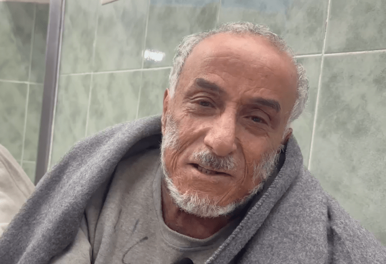 elderly man wrapped in a grey UN blanket at the hospital where he's being treated after torture
