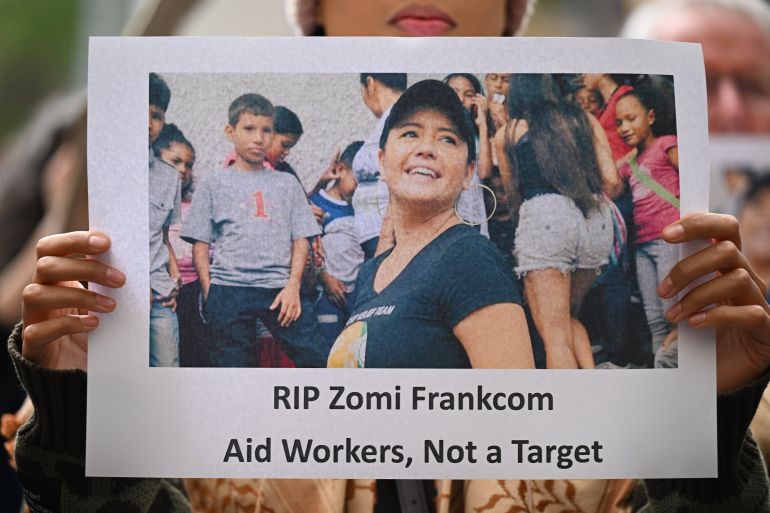 a person holds a sign saying RIP Zomi Frankcom aid workers not a target