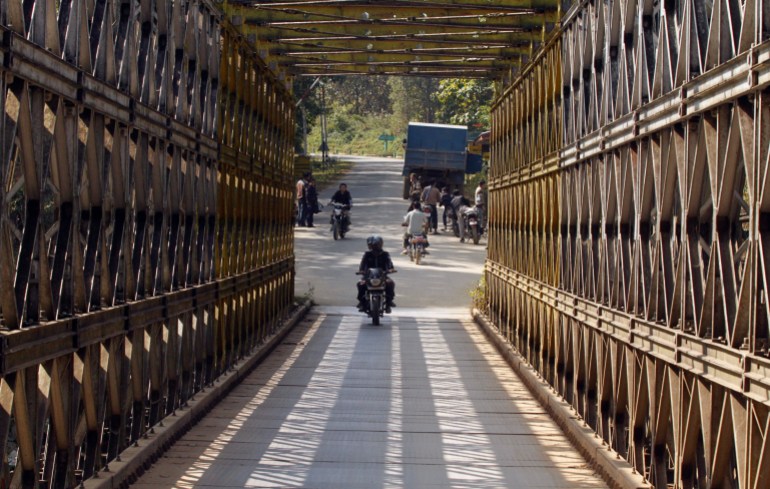 People ride motorbikes as they cross Indo-Myanmar border bridge at the border town of Moreh, in the northeastern Indian city of Imphal