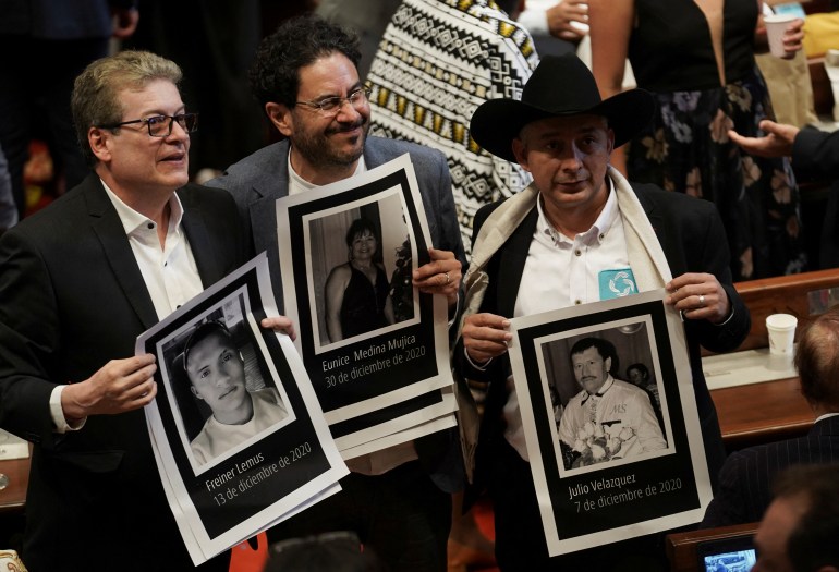 Três políticos: o representante Alirio Uribe, o senador Ivan Cepeda e o ativista William Aljure Martinez seguram fotos em preto e branco de ativistas mortos durante o conflito na Colômbia. 