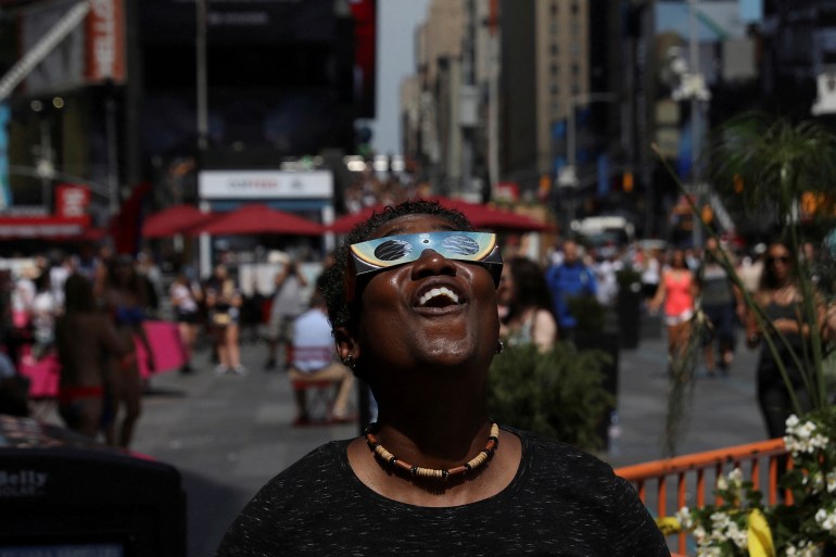 A woman views a solar eclipse at Times Square in New York City