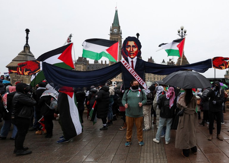 protestors waving palestinian flags carry an effigy showing Justin Trudeau 