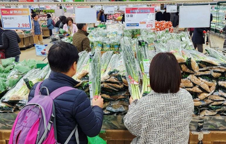 Women looking at a display of green onions in Seoul