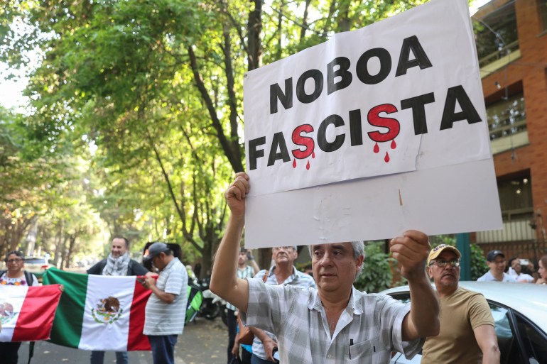 A protester in Mexico holds up a sign that says, "Noboa Fascista."