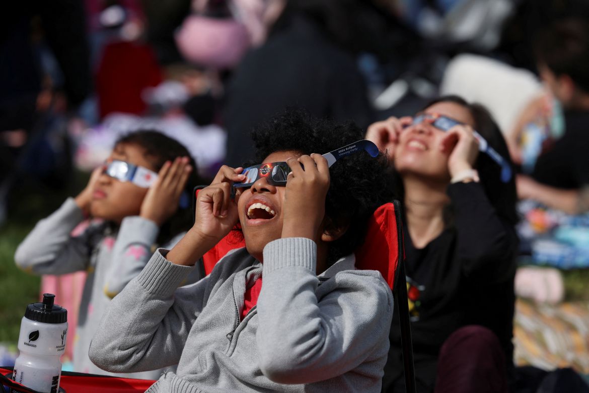Children smile as the eclipse unfolds above them.